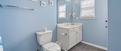 A bathroom with a toilet, sink, vanity, and a mirror.