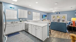 Una cucina con mobili bianchi, un piano di lavoro blu e un'area pranzo con un divano blu e una lampada.