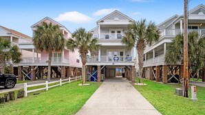 Un hotel sulla spiaggia con diversi balconi, una galleria coperta e palme.