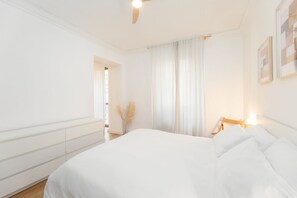 A bedroom with a large bed, a ceiling fan, a nightstand with a lamp, and a window with curtains. - Torino | Belfiore House 59  (Torino)