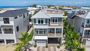 Una moderna zona residencial costera con varias casas de dos pisos, balcones, vista al mar y entrada pavimentada.