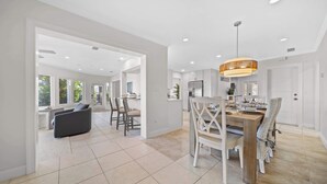 A spacious, modern kitchen with white cabinetry, a central island, and a hanging light fixture. - Infinite Views! Heated Pool! Directly on Tampa Bay (Holmes Beach)