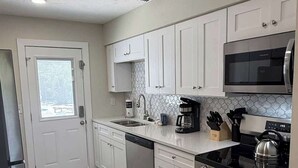 Uma cozinha moderna com armários brancos, eletrodomésticos de aço inoxidável e painel de azulejos.