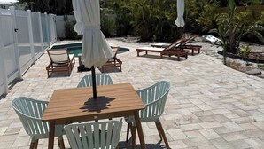 Um pátio com piscina, móveis de exterior e palmeiras.