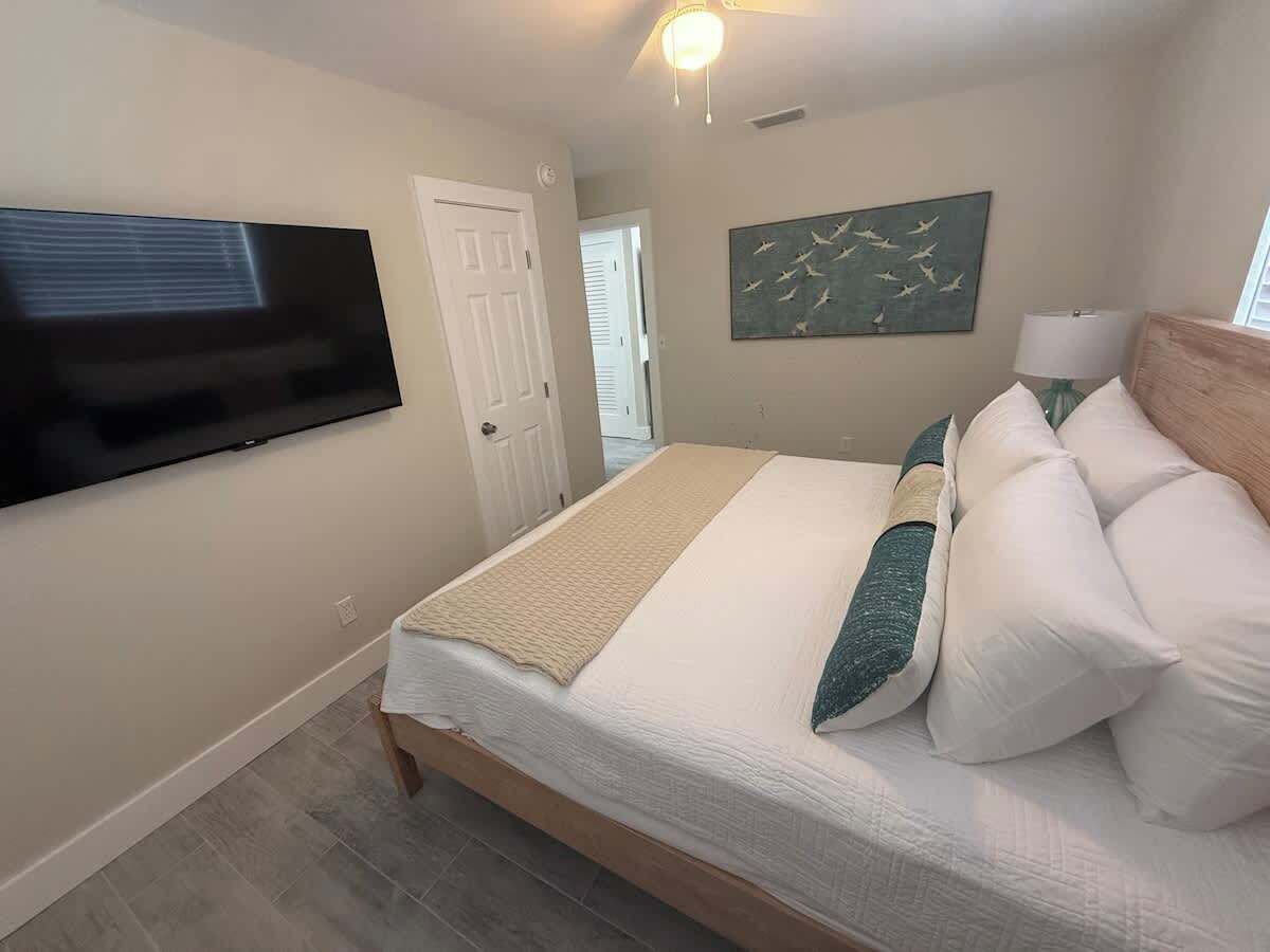 A bedroom with a bed, a television mounted on the wall, and a door.