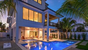 Una moderna casa a due piani con piscina, area salotto esterna e patio coperto.