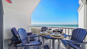 A balcony with a table set for two, overlooking a beach. - New! Beachfront Paradise! ~Heated Pool! Top Floor (Holmes Beach)