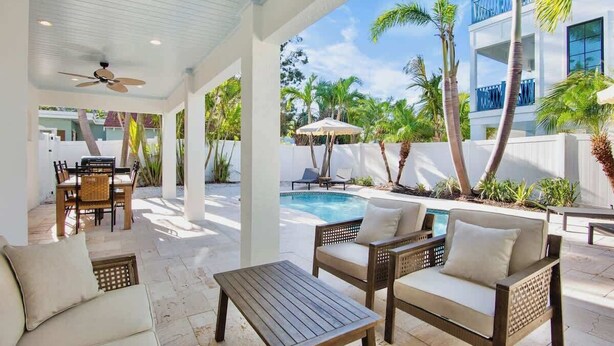 An outdoor patio with a pool, lounge chairs, and a dining area. - Birdsong-Steps to Bean Point Beach Heated Pool! (Anna Maria)