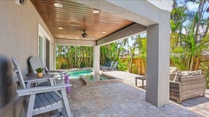 Un portico coperto con piscina, mobili da esterno e rigogliosa vegetazione.