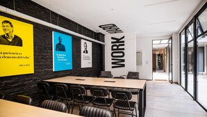 Een moderne vergaderzaal met een lange tafel, zwarte lederen stoelen en een groot bord waarop 'WORK HARD' staat.