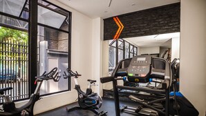 Een sportschool met trainingsapparatuur, waaronder een loopband, hometrainer en elliptische machine.