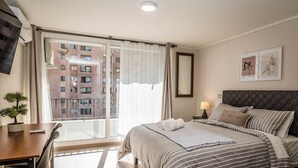 Een hotelkamer met een groot bed, een bureau en uitzicht op een gebouw door een raam.