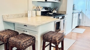 A modern kitchen with a central island, bar stools, a microwave, and a stove. - Boston Condo with Free Parking (Boston)