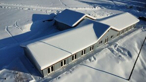 Un edificio cubierto de nieve con una estructura larga y estrecha, múltiples ventanas y un techo inclinado.