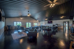 A spacious indoor area with a high ceiling, multiple seating arrangements, and a television screen mounted on the wall. - The Orion (Fairbanks)