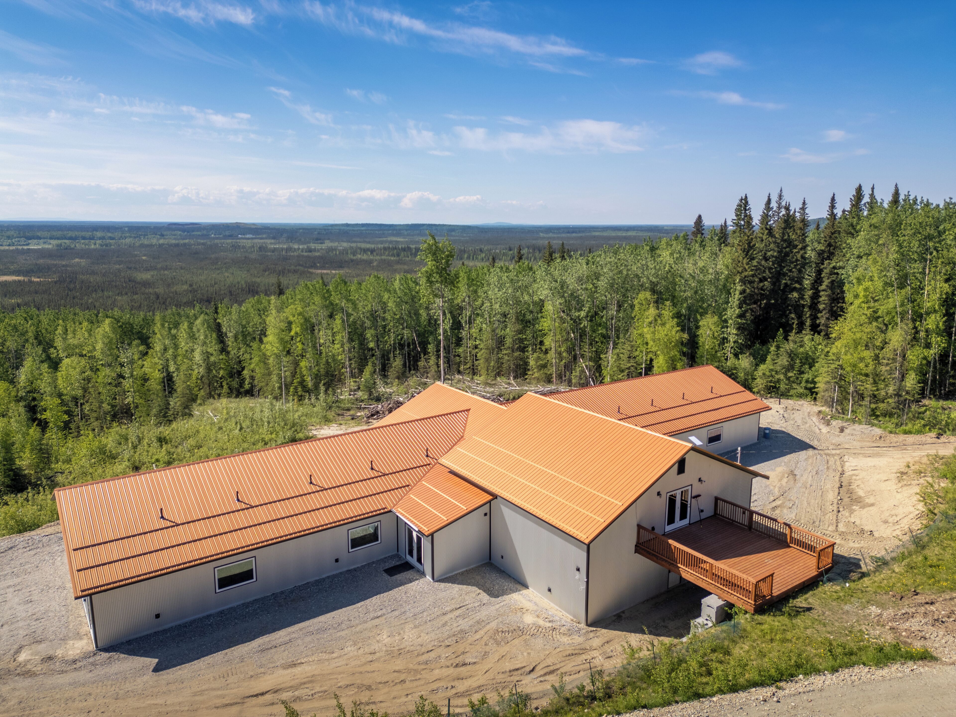 A modern two-story building with a sloped roof, surrounded by a forested landscape.