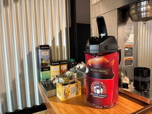 Une machine à café avec une étiquette indiquant « Mélange Mushers » et un récipient contenant du thé au « citron et gingembre ».
