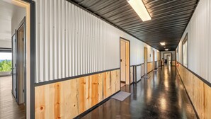 Un largo pasillo con paneles de madera y paredes de metal, que conduce a varias puertas.