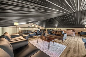 A spacious living area with leather sofas, a coffee table, and a patterned rug. - The Orion (Fairbanks)