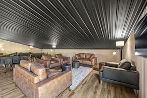 A modern interior with leather sofas, a dining area, and a unique ceiling design. - The Orion (Fairbanks)