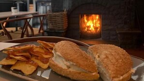 Un comedor con chimenea, un plato de nachos y sándwiches, y una cabeza de venado montada en la pared.