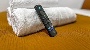 A remote control and two rolled-up towels on a textured bed. - Modern Studio Apartments in Nürnberg (Stein)