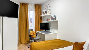 A hotel room with a bed, a desk with a computer, a chair, and a window with curtains. - Modern Studio Apartments in Nürnberg (Stein)
