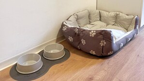 A corner room with a pet bed and two bowls on the floor. - Modern Studio Apartments in Nürnberg (Stein)
