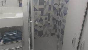 Ein Badezimmer mit Dusche, Waschbecken und Spiegel.