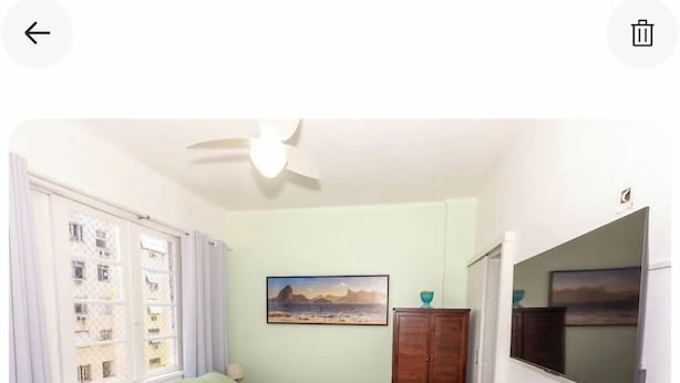 Ein Schlafzimmer mit Bett, Kleiderschrank, Fernseher und einem Fenster mit Vorhängen.