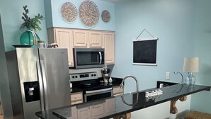 A modern kitchen with a central island, stainless steel appliances, and a light blue wall. - Gulf front 2-2 condo with indoor/ outdoor poo! Close to restaurants and shopping (Orange Beach)