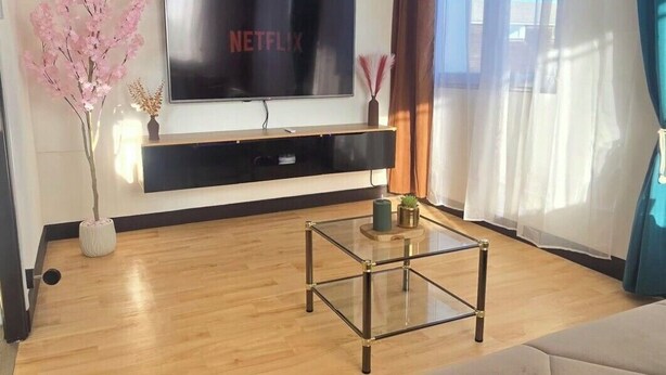 A modern living room with a flat-screen TV, a glass coffee table, and a sofa. - Quiet apartment Vittel - Near the thermal baths (Norroy)