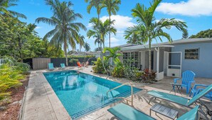 Une piscine avec des chaises longues et un espace patio couvert.
