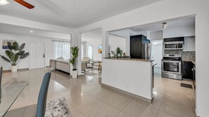 Une cuisine moderne dotée d’appareils électroménagers en acier inoxydable, d’un îlot central et d’un coin repas avec une table et des chaises en verre.