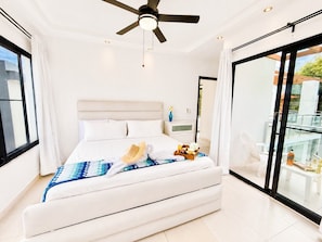 A modern bedroom with a large bed, a ceiling fan, and a balcony with a glass railing. - 5 bd villa with rooftop in Sosua Ocean Village (Sosúa)