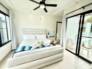 A modern bedroom with a bed, a ceiling fan, a nightstand, and a view of the outside. - 5 bd villa with rooftop in Sosua Ocean Village (Sosúa)