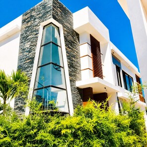 A modern building with a prominent glass facade and a stone accent wall. - 5 bd villa with rooftop in Sosua Ocean Village (Sosúa)