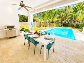 An outdoor dining area with a pool, a ceiling fan, and a kitchen area with a microwave. - 5 bd villa with rooftop in Sosua Ocean Village (Sosúa)