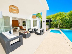 Ein moderner Außenbereich mit Korbmöbeln, einem Pool und üppiger Bepflanzung.