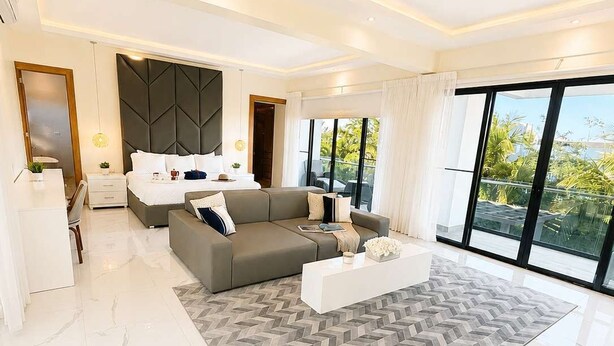Ein modernes Wohnzimmer mit einer Couch, einem Couchtisch und einem großen Fenster mit Blick auf viel Grün.