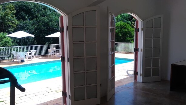 An open doorway leading to a swimming pool area with a view of the pool and surrounding greenery.