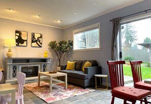 A living room with a fireplace, a sofa, a coffee table, and a view of the outdoors. - A Rather Posh 4 BR Renton Retreat with AC (Renton)