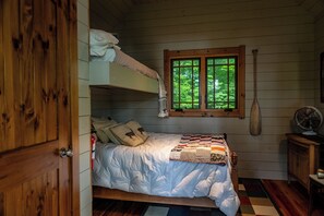 A cozy bedroom with a bunk bed, a wooden window, a fan, and a rustic wooden door. - Private Adirondack Compound! (Saint Regis Falls)
