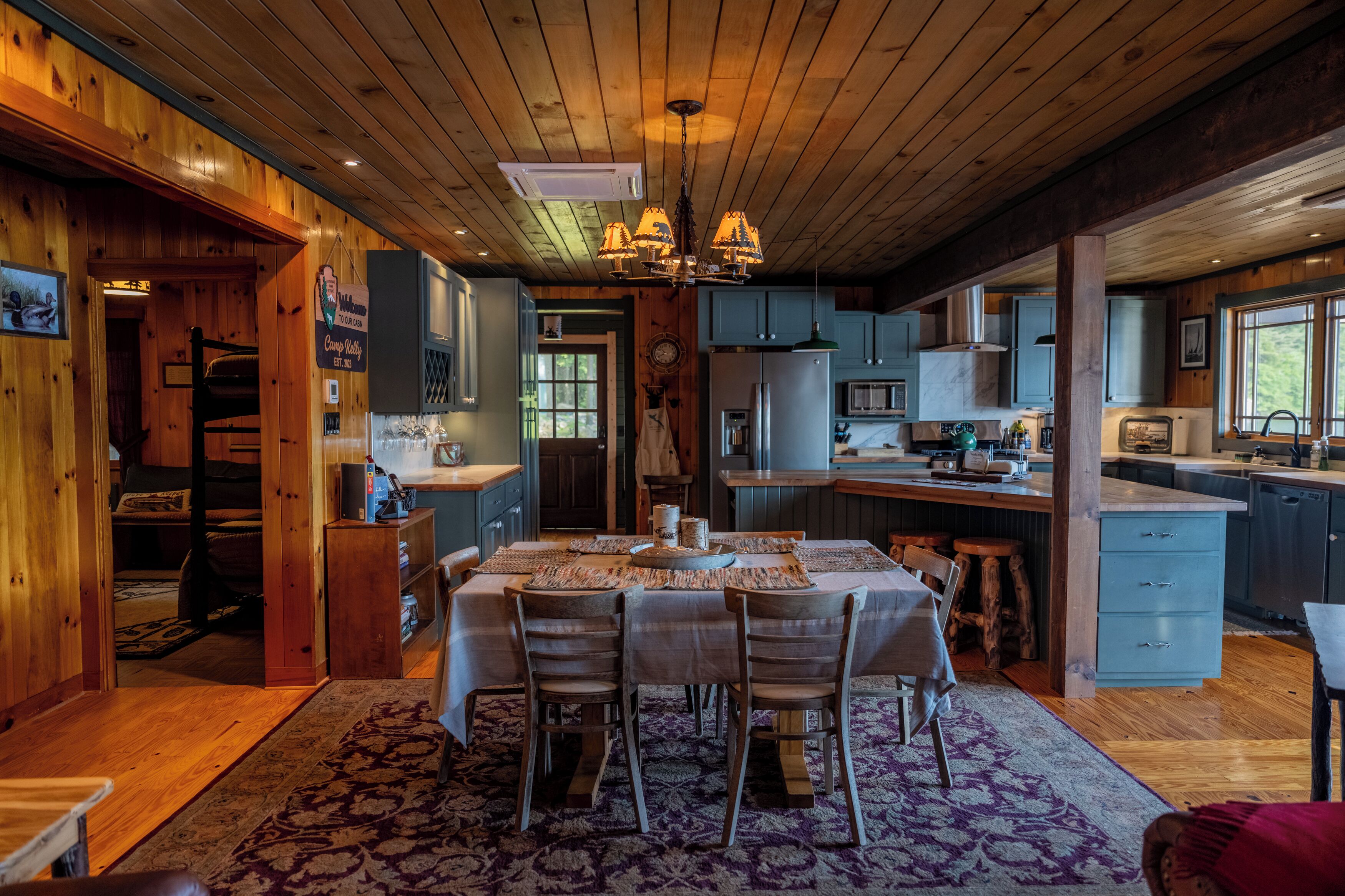 Une cuisine spacieuse avec des meubles en bois, un coin repas avec une table dressée pour quatre personnes et un grand lustre.