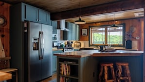 A kitchen with a large island, built-in bookshelves, and rustic wooden accents. - Private Adirondack Compound! (Saint Regis Falls)
