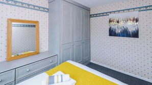 A bedroom with a bed, a wardrobe, a mirror, and a wall-mounted painting. - Spacious 3 Bedroom Home in Westhoughton (Westhoughton)