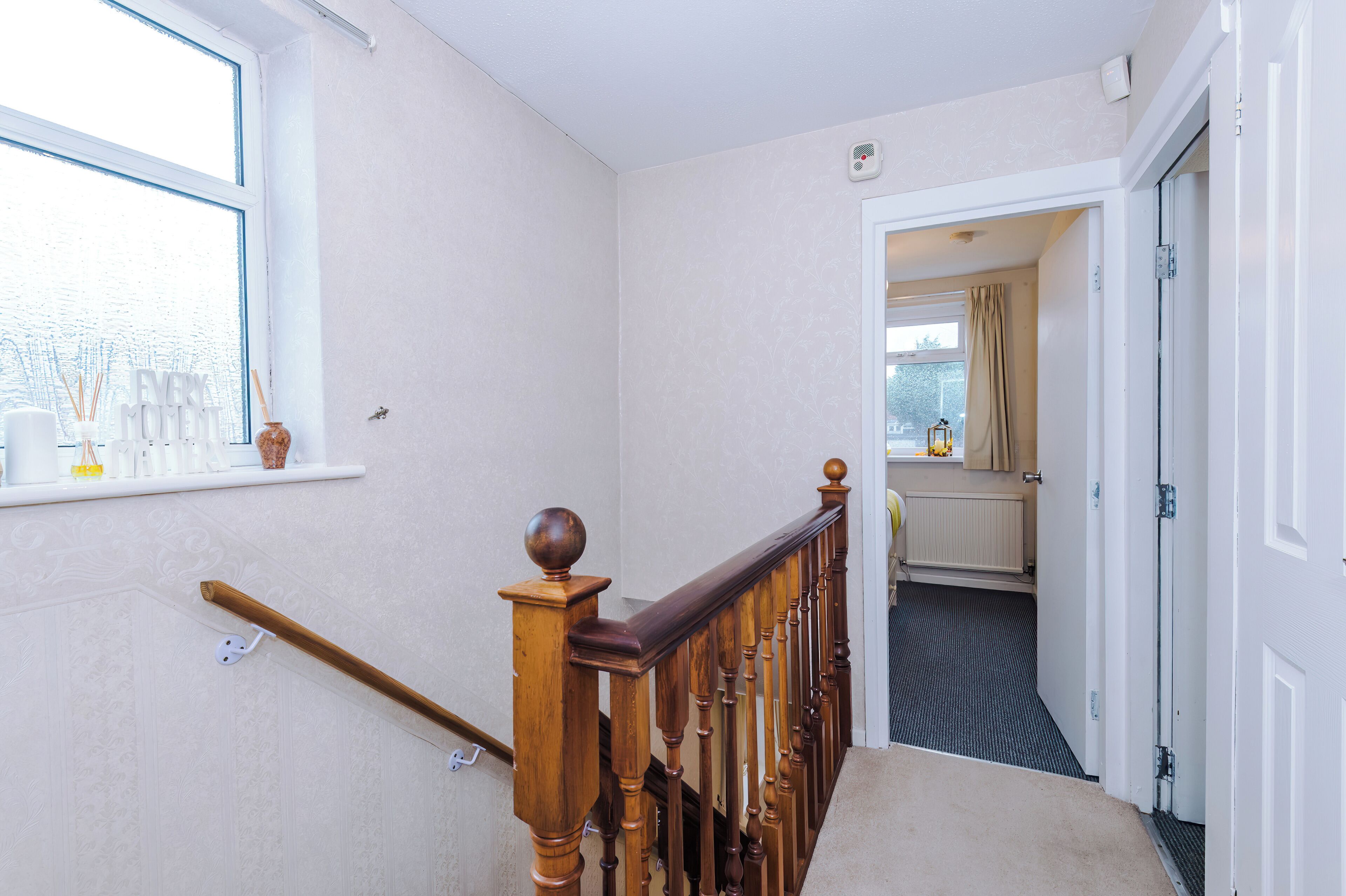 A hallway with a wooden staircase, a radiator, and a door leading to another room.