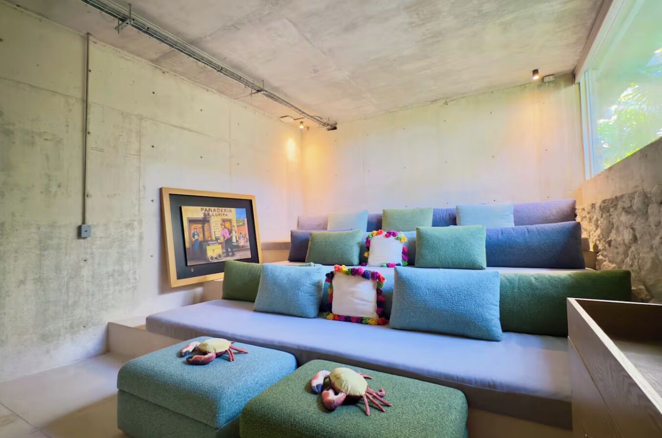 Una sala de estar moderna con un conjunto de sofá, almohadones coloridos y un cuadro en la pared.