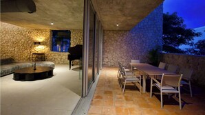 Eine Terrasse im Freien mit einer Steinmauer, einem Klavier, einem runden Tisch und einem Esstisch-Set.