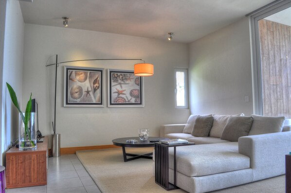 A modern living room with a sofa, coffee table, and artwork on the wall. - Oceanfront 2BR at Ultravioleta Cabarete | Fast WiFi, Balcony & Parking (Cabarete)